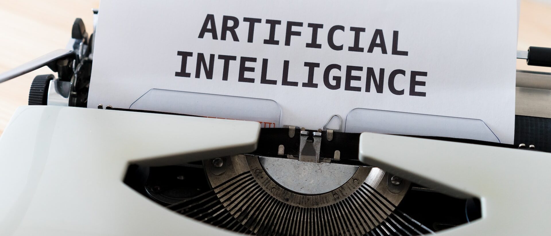 Ein Blatt ragt aus einer Schreibmaschine auf diesem steht: artificial intelligence