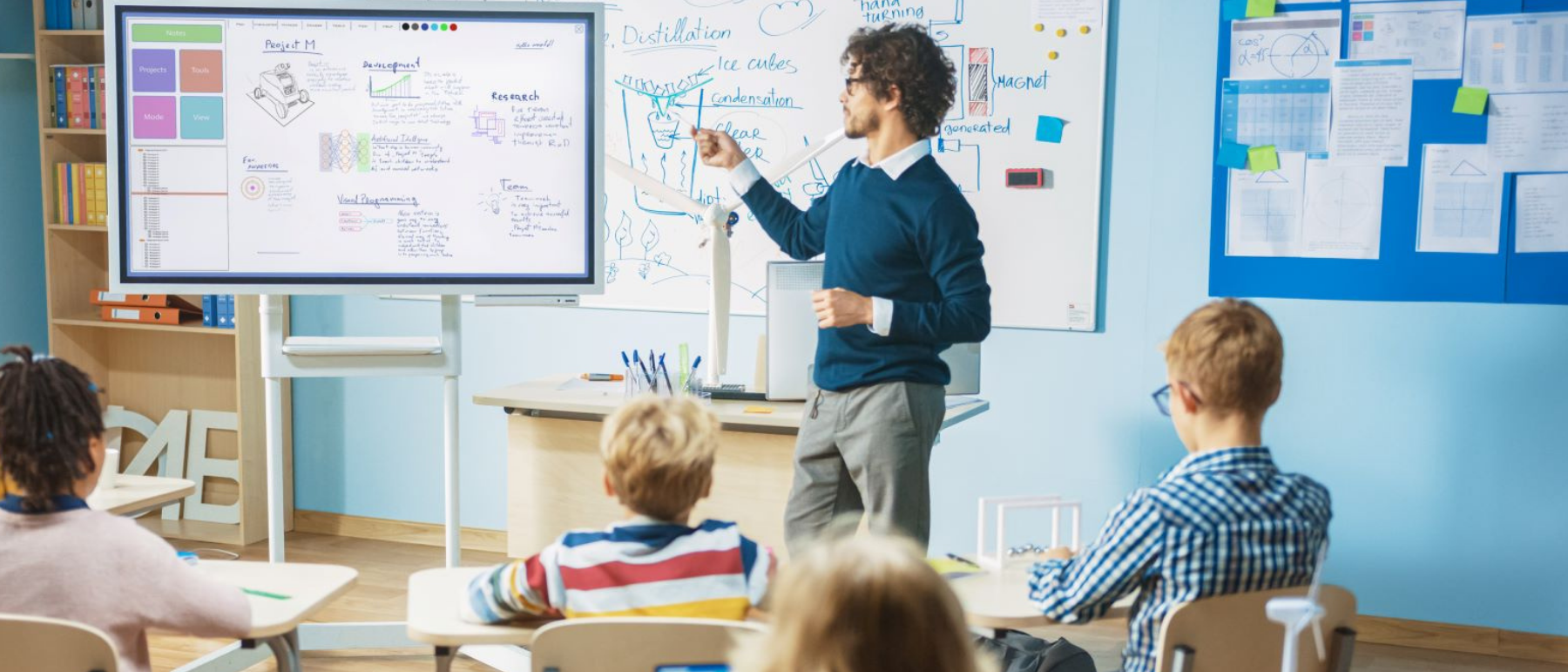 Lehrer steht an einer Tafel vor seiner Schulklasse