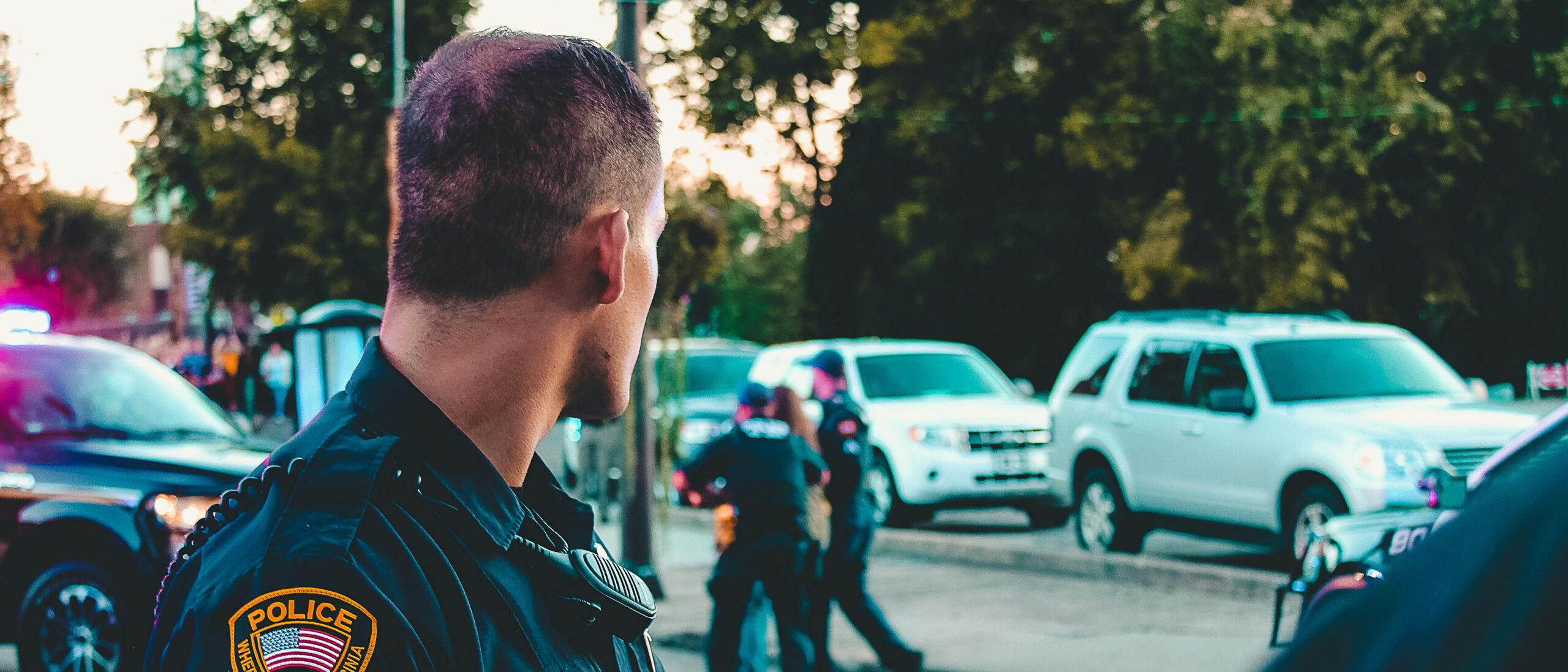 Polizist blickt auf einen Polizeieinsatz seiner Kolleg*innen.