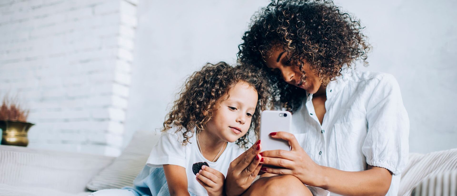 Mutter zeigt ihrer Tochter etwas auf dem Handy