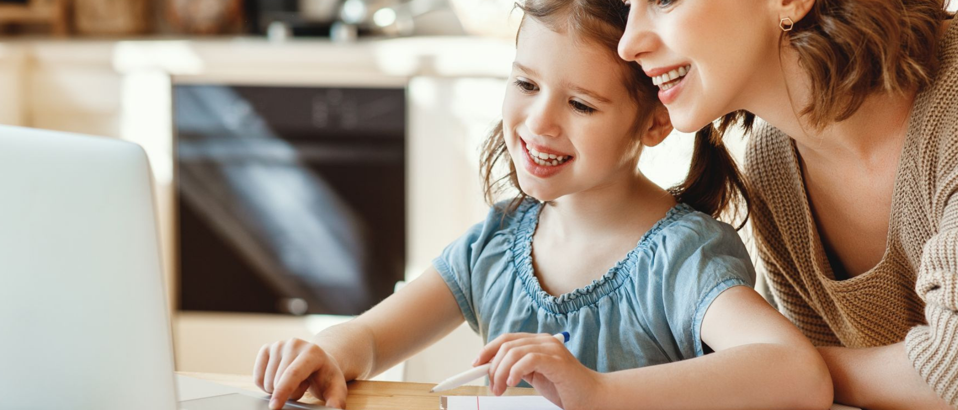 Mutter sitzt mit Tochter gemeinsam vor dem Laptop