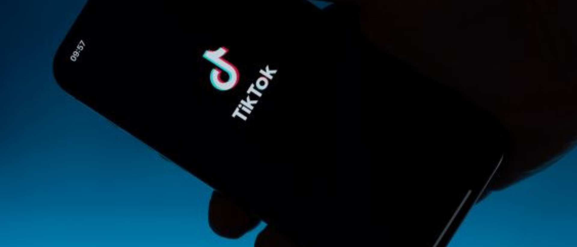 Hand hält Handy auf desen Screen TikTok Startfenster zu sehen ist.