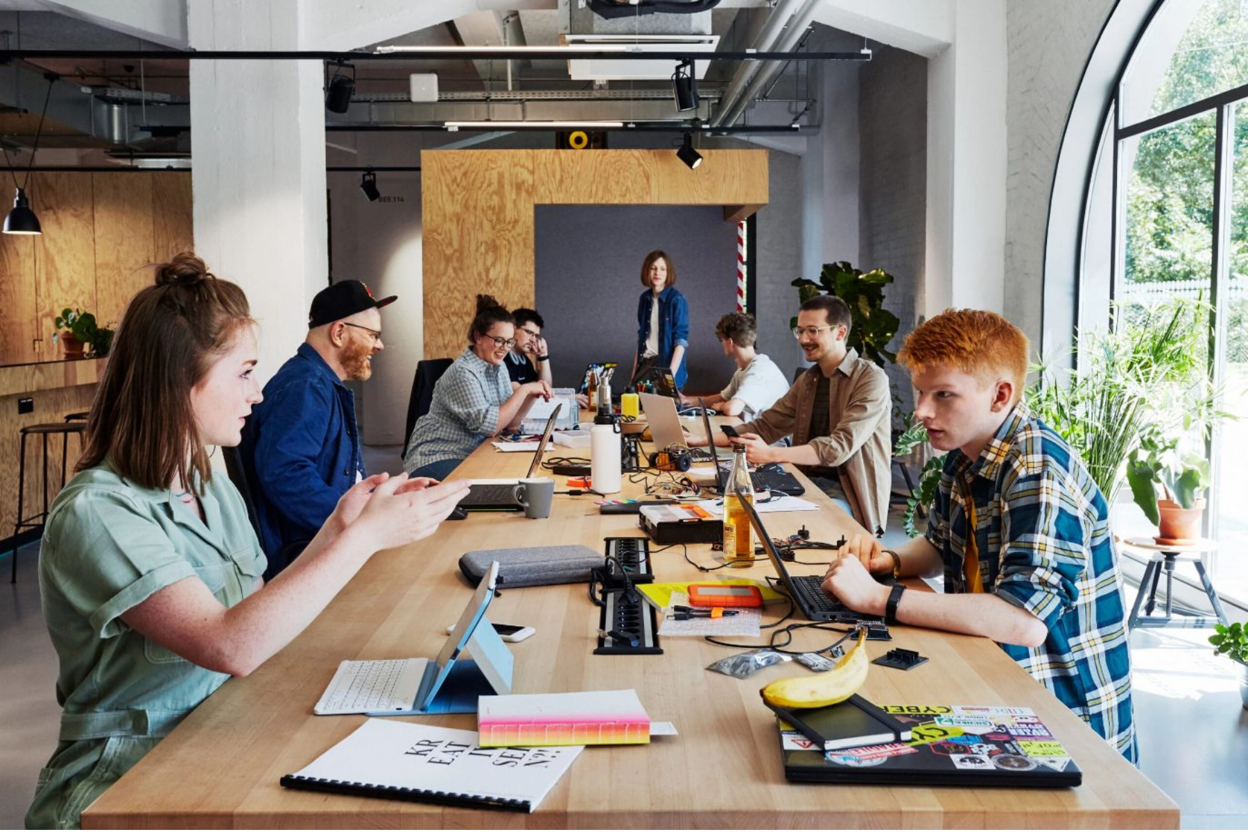 Mehrer Menschen sitzen sich an einem langen Tisch mit ihren Laptops gegenüber