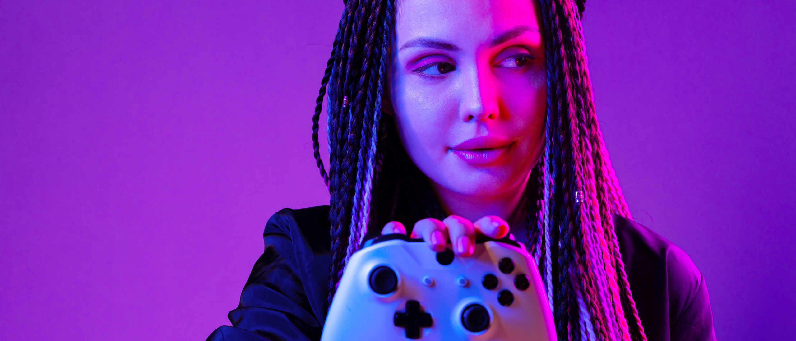 Junge Frau mit langen Zöpfen hält Konsolen-Joystick