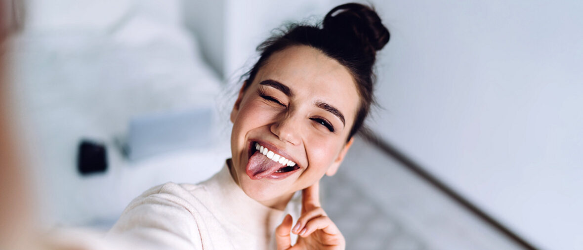 Frau macht Selfie mit lustigem Gesichtsausdruck