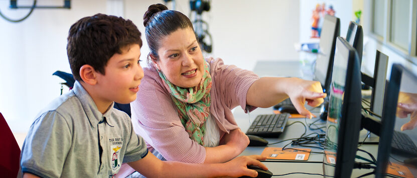 Frau zeigt einem Jungen etwas am Computer