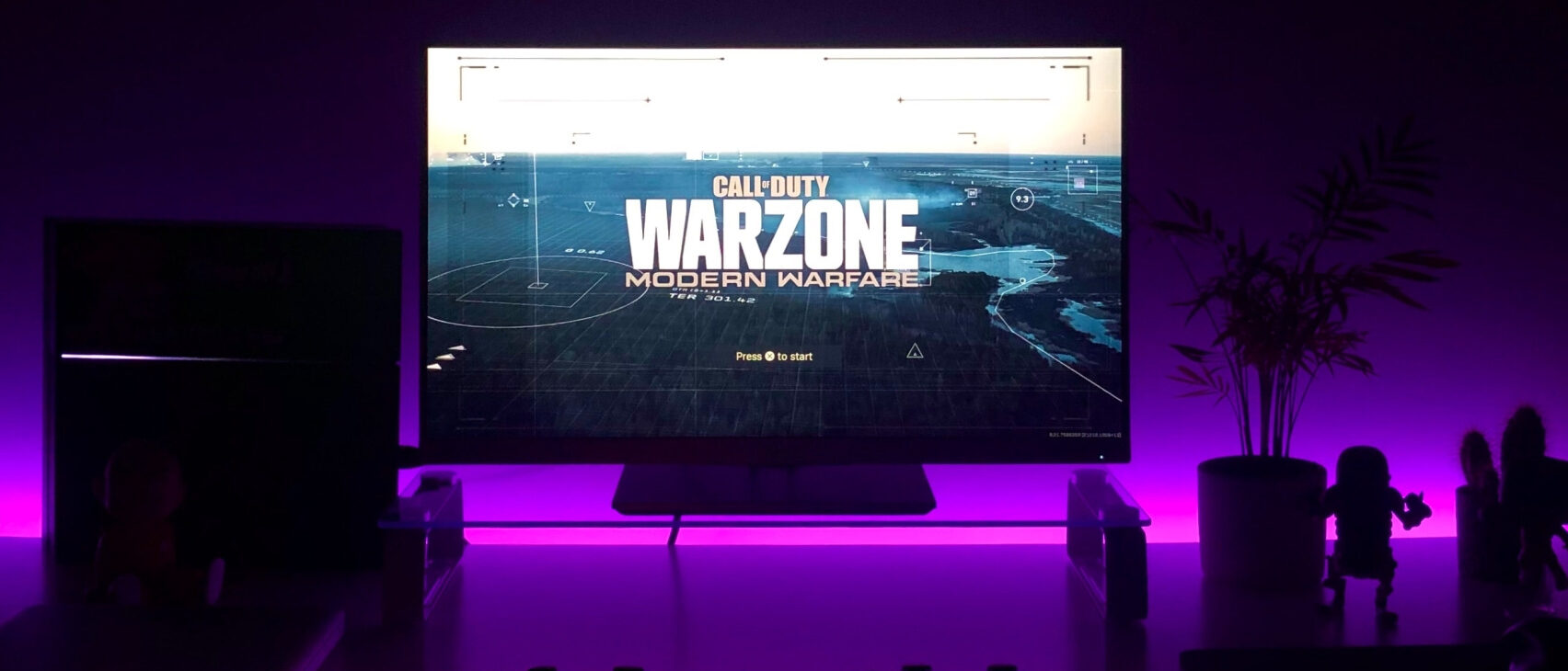 Ein dunkles Zimmer mit einem großen Bildschimr auf dem "Warzone" läuft