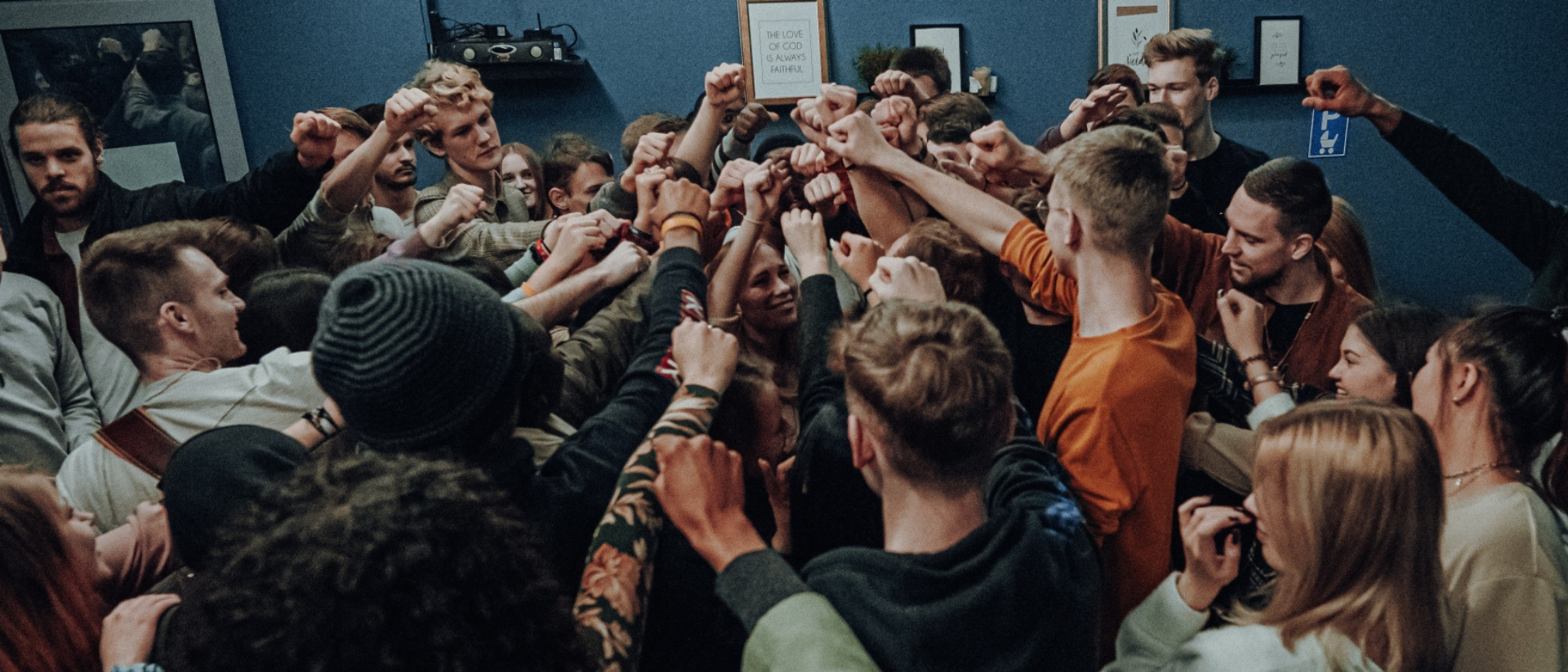 Eine Gruppe von Jugendlichen und jungen Menschen steht in einem Kreis und hebt die Habd geballt zur Faust in die Mitte