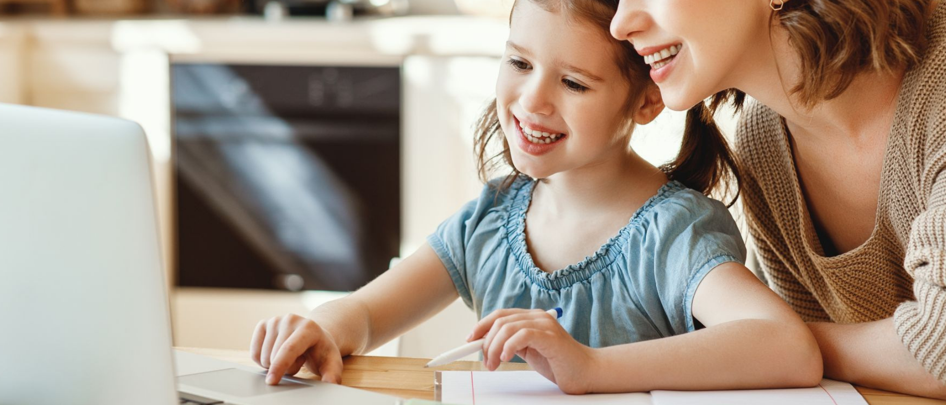 Mutter sitzt mit Tochter gemeinsam vor dem Laptop