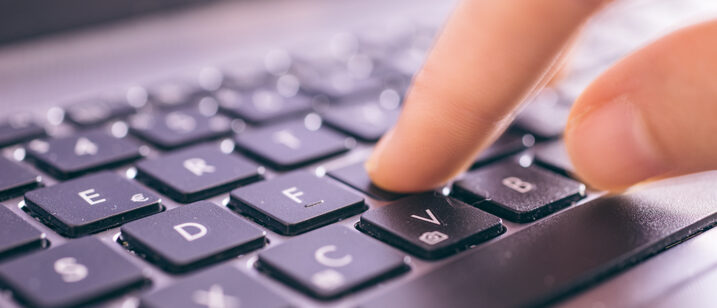 Jemand tippt auf einer Tastatur, die in Großaufnahme zu sehen ist