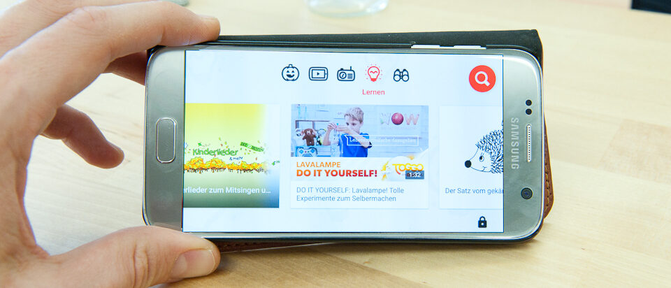 Hand hält Handy auf dem YouTube Kids läuft