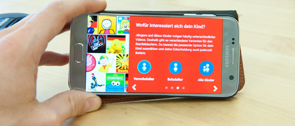 Hand hält Handy auf dem YouTube Kids läuft.