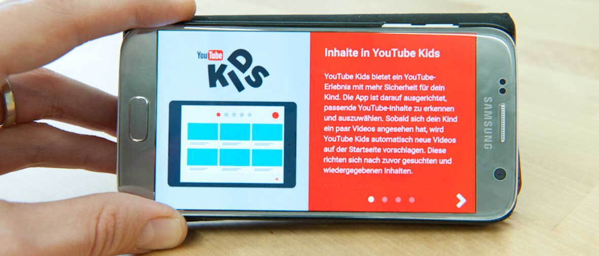 Hand hält Handy auf dem YouTube Kids läuft.