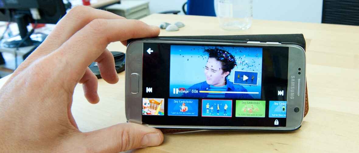 Hand hält Handy auf dem YouTube Kids läuft