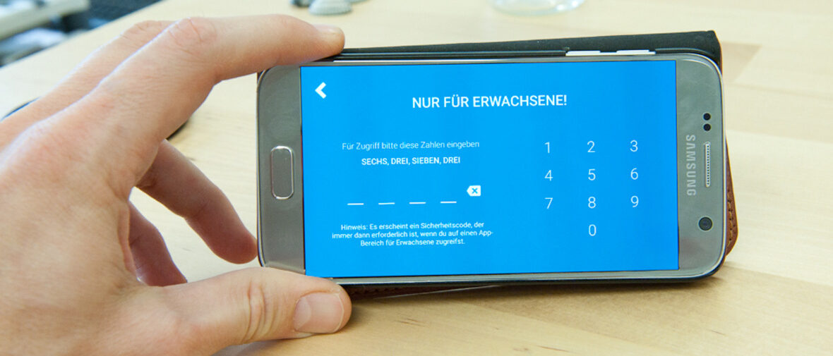 Hand hält Handy auf dem YouTube Kids Code-Eingabe zu sehen ist.
