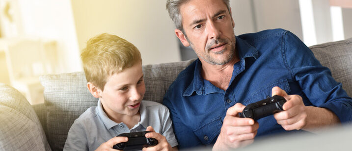 Vater und Sohn auf dem Sofa mit Spielcontroller