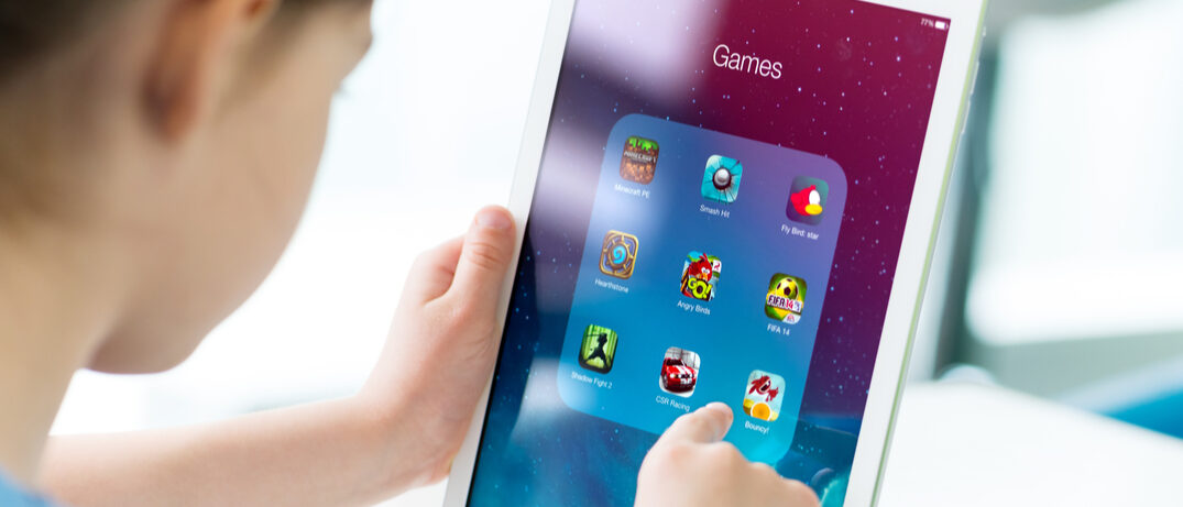 Schrägprofil eines Kindes am iPad mit verschiedenen Spieleapps
