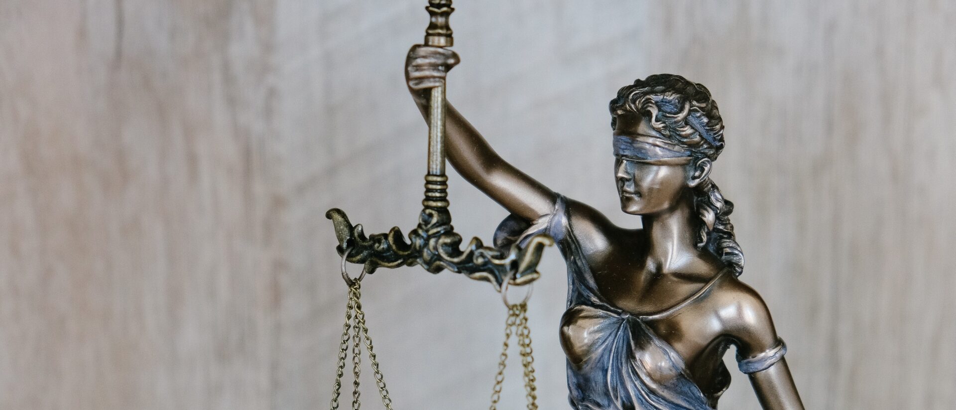 Statue der Justizia, die eine Waage in der Hand hält und ihre Augen verbunden hat.