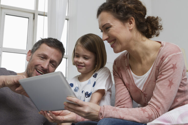 Eltern schauen gemeinsam mit ihrm Kind ins iPad