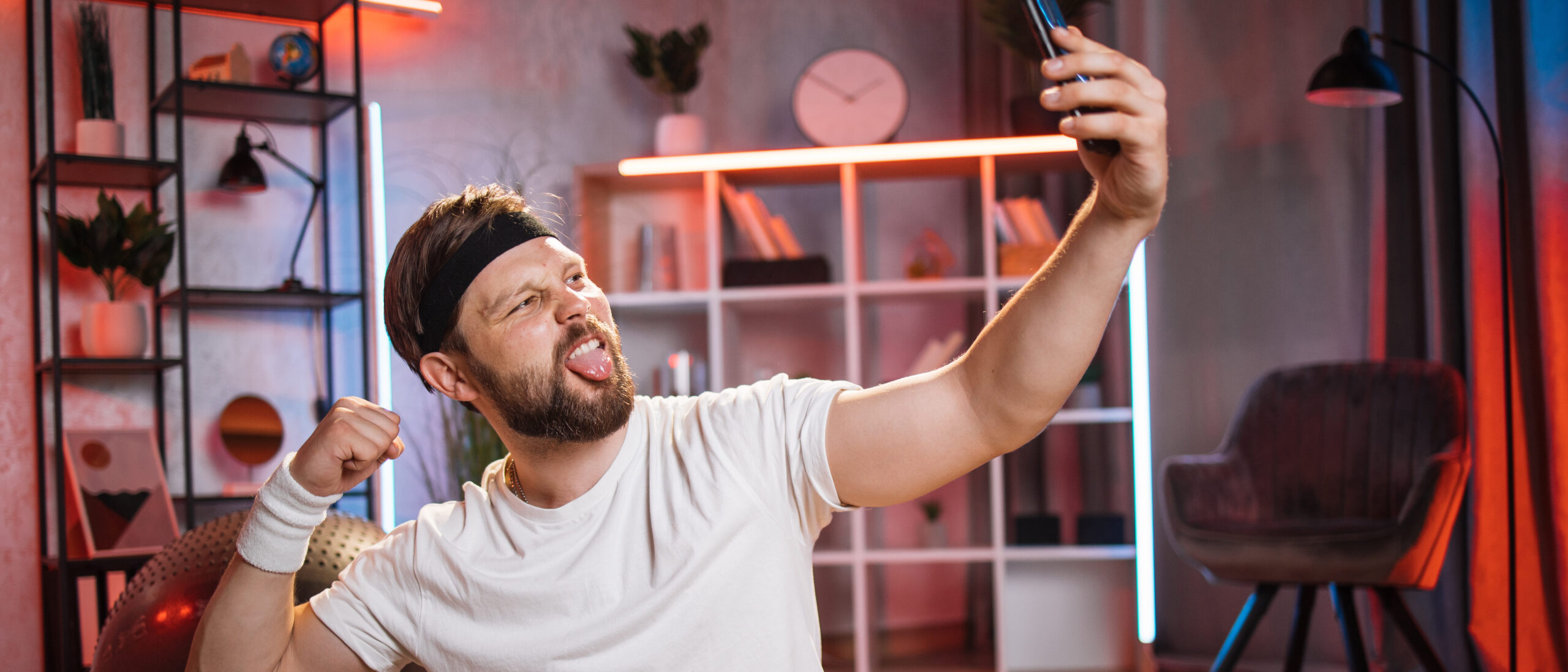 Mann im Sportoutfit flext seinen Arm in seine Handykamera