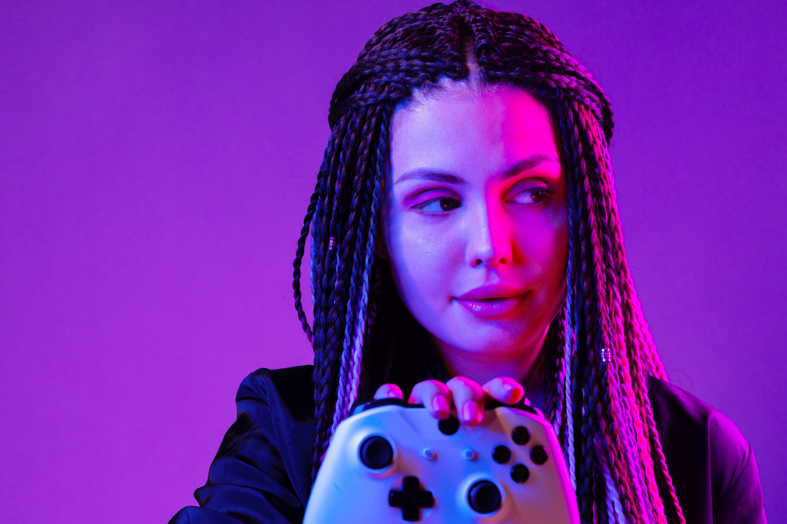 Junge Frau mit langen Zöpfen hält Konsolen-Joystick