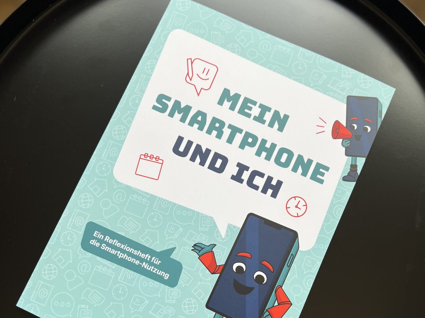 Das Arbeitsheft "Mein Smartphone und ich" liegt in einer Pfanne.