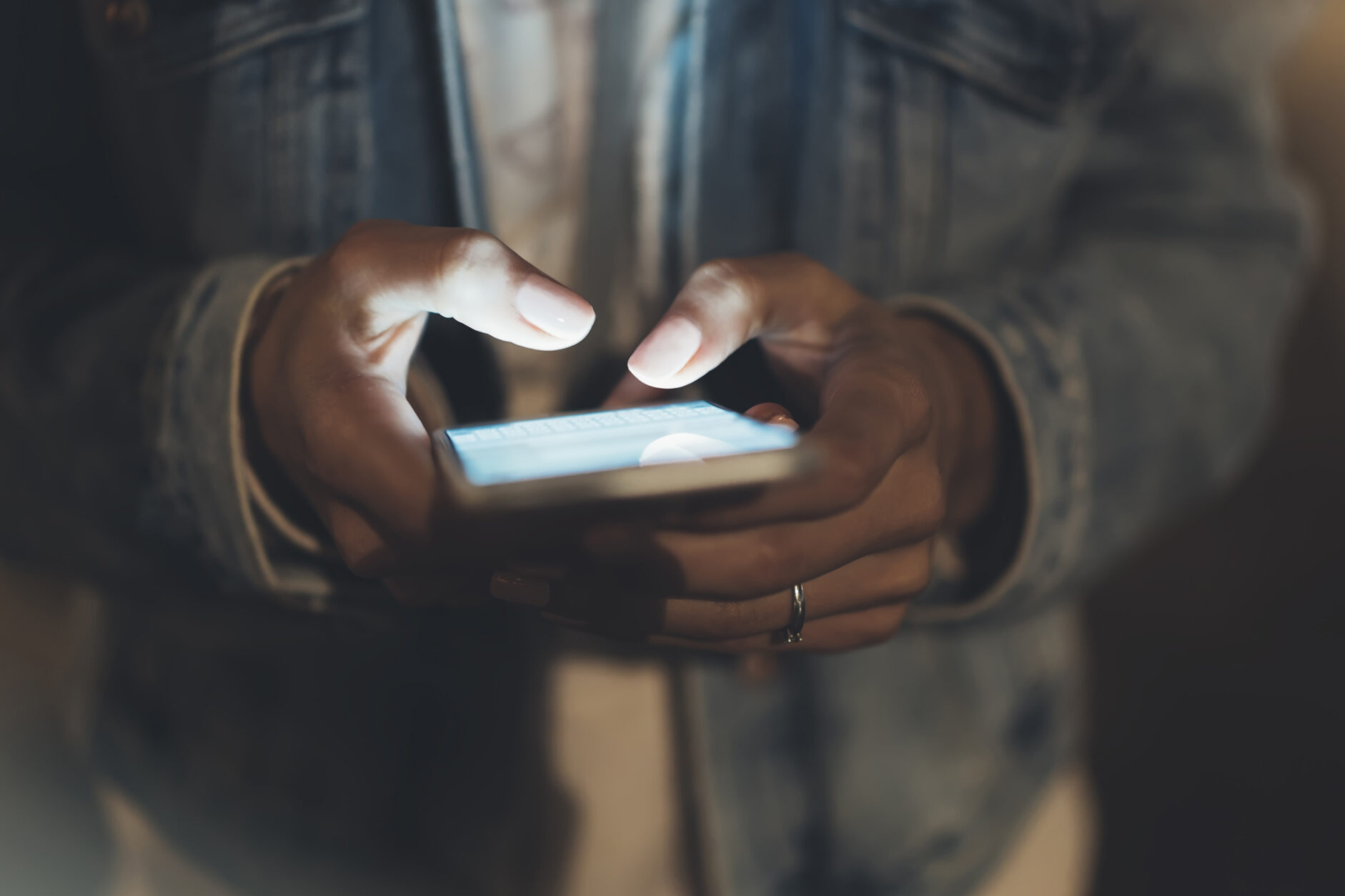 Zwei Hande die ein Smartphone halten, dessen Bildschirm hell erleuchtet ist