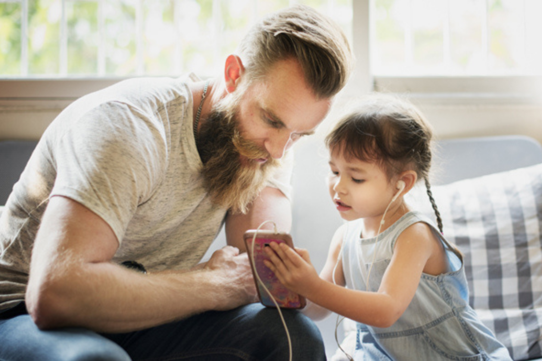 Vater schaut mit seiner Tochter gemeinsam in ein Handy