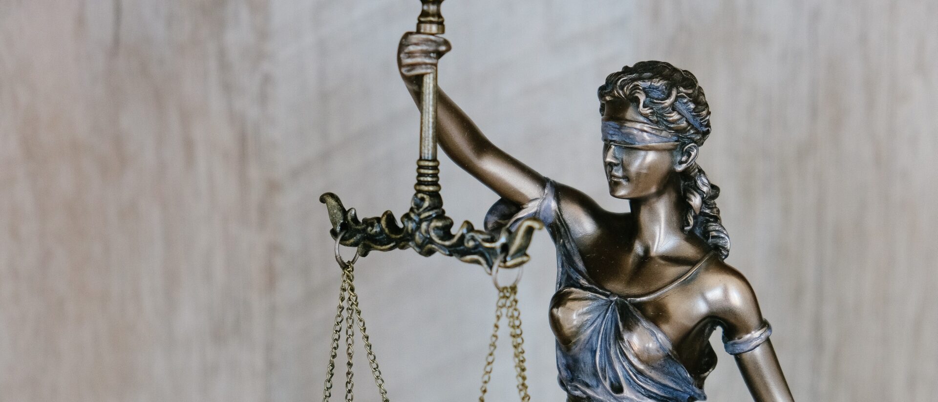 Statue der Justizia, die eine Waage in der Hand hält und ihre Augen verbunden hat.