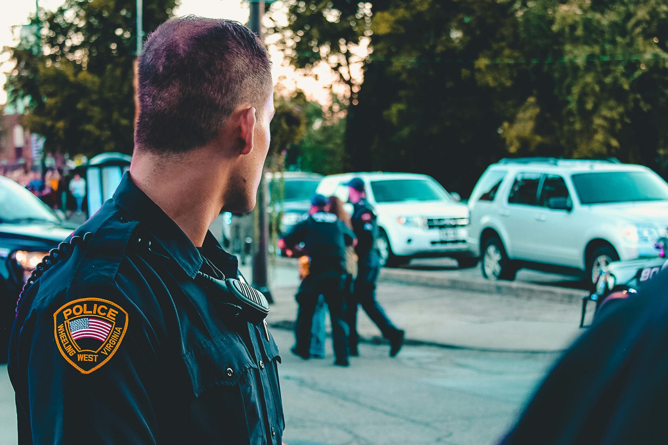 Polizist blickt auf einen Polizeieinsatz seiner Kolleg*innen.