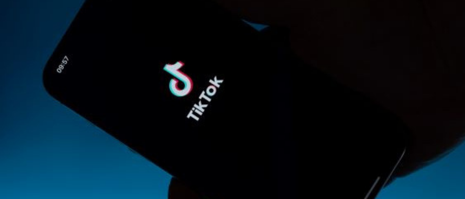 Hand hält Handy auf desen Screen TikTok Startfenster zu sehen ist.