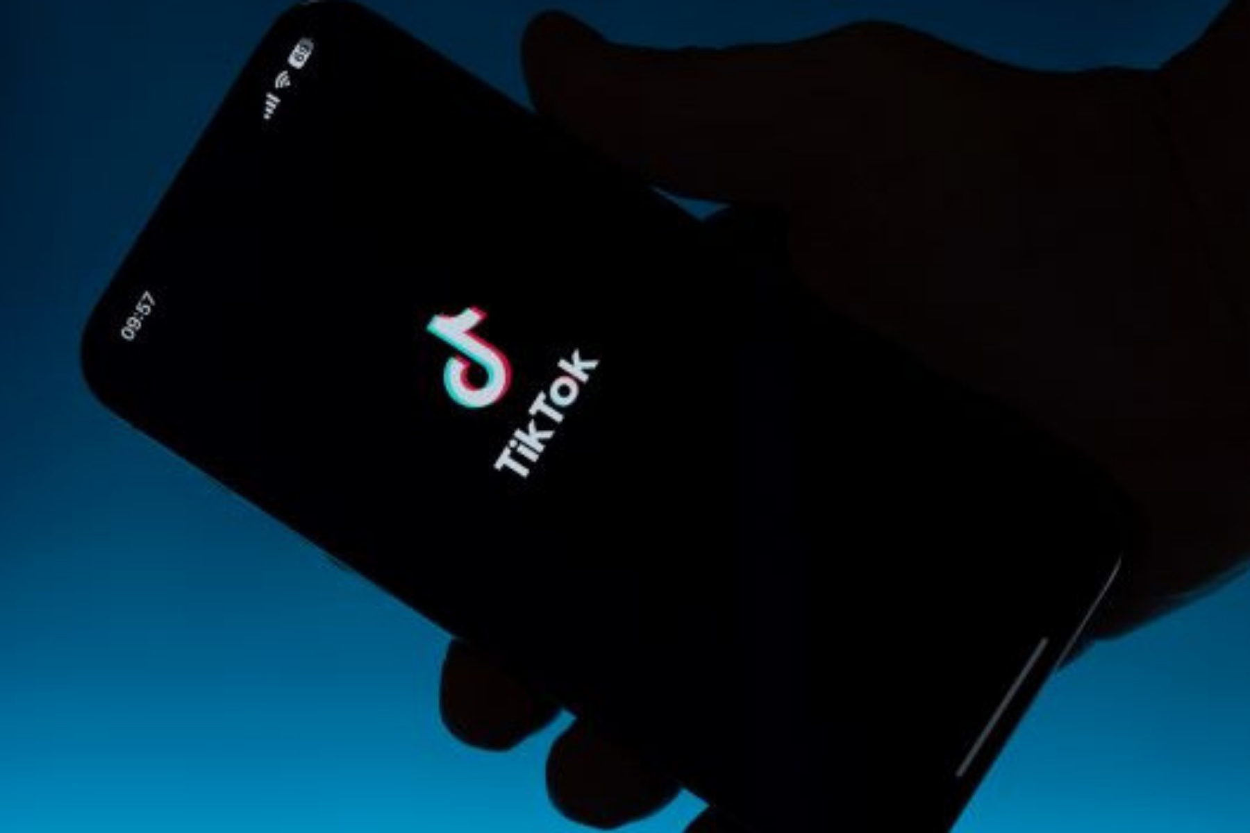 Hand hält Handy auf desen Screen TikTok Startfenster zu sehen ist.
