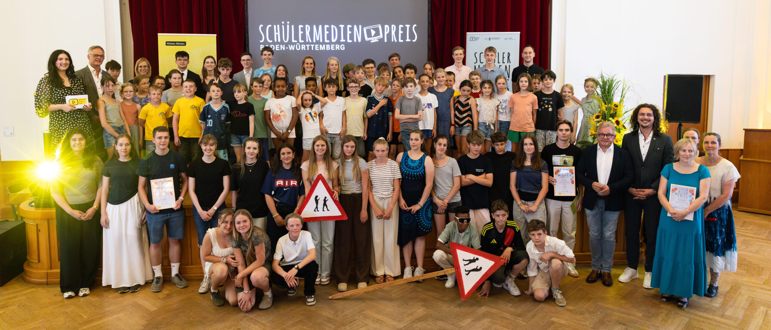 Gruppenfoto auf der Bühne aller Gewinnerinnen und Gewinner des Schülermedienpreises 2026 zusammen mit Wiebke Wiesner, Rudi Hoogvliet und der Moderatorin.