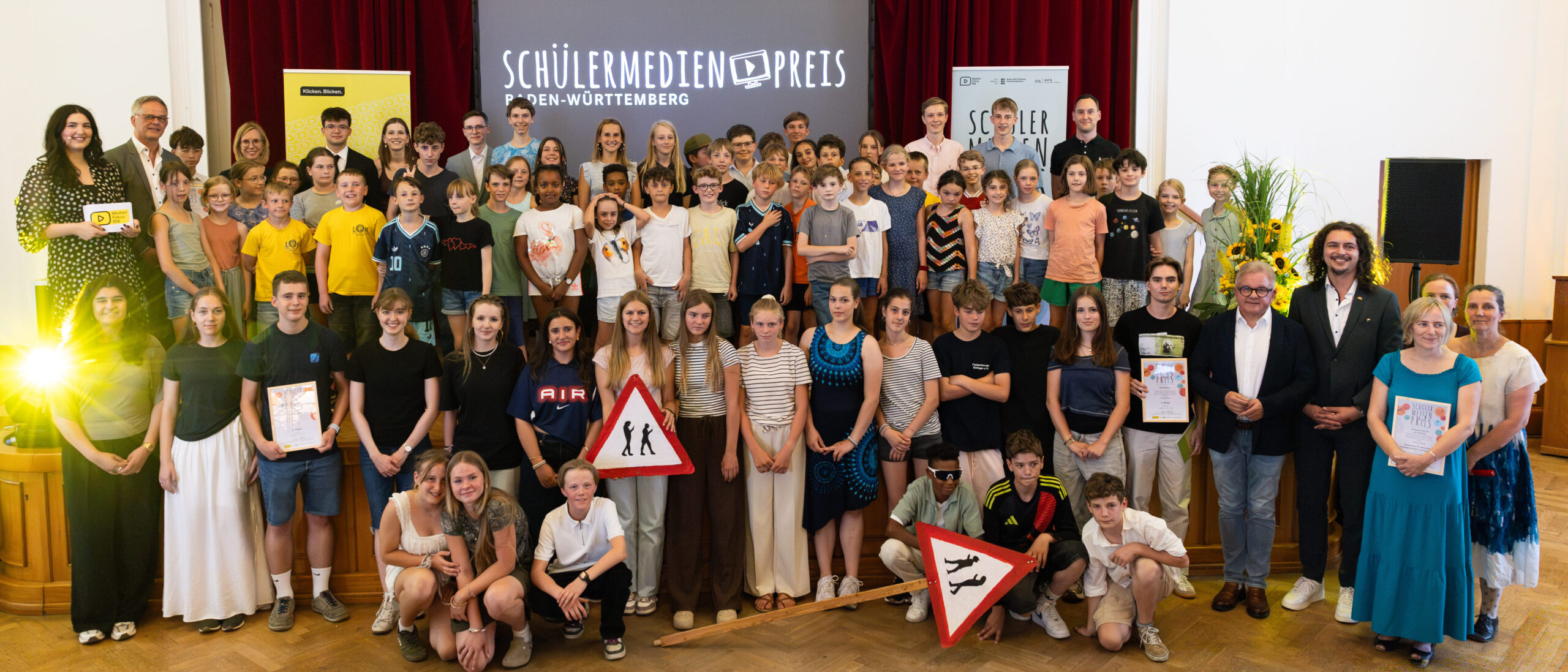 Gruppenfoto auf der Bühne aller Gewinnerinnen und Gewinner des Schülermedienpreises 2026 zusammen mit Wiebke Wiesner, Rudi Hoogvliet und der Moderatorin.